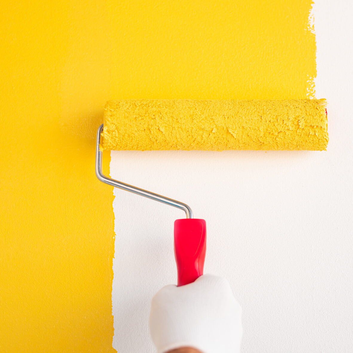 Malowanie wałkiem białej ściany żółtą farbą